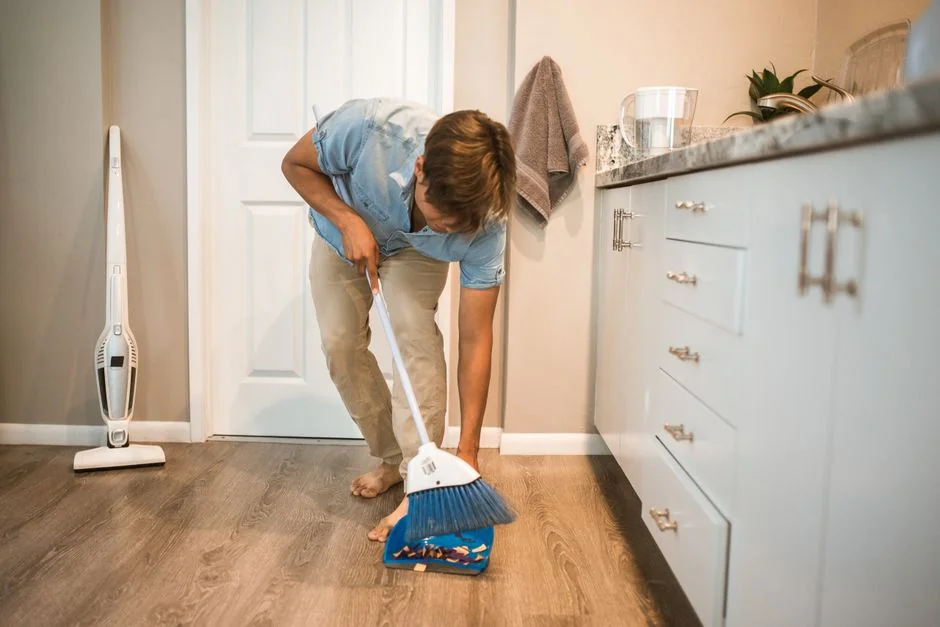 home-img A man cleaning a glass door indoors using a spray bottle and cloth.